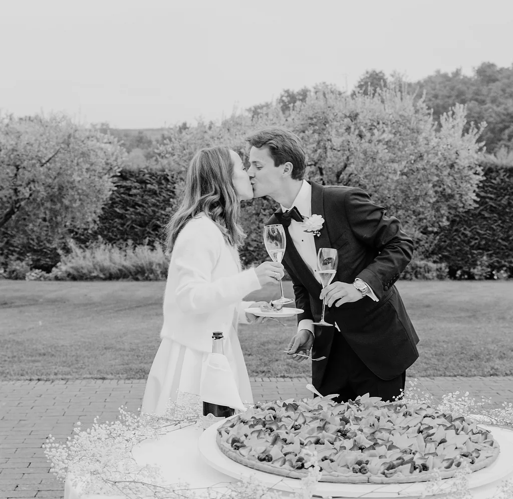 Romantischer Kuss über der traditionellen italienischen Hochzeitstorte in Schwarz-Weiß.